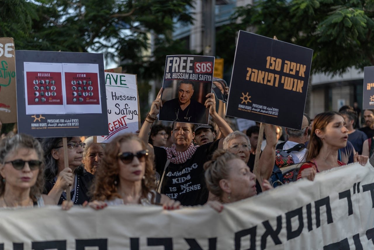Protesters display signs in English and Hebrew.