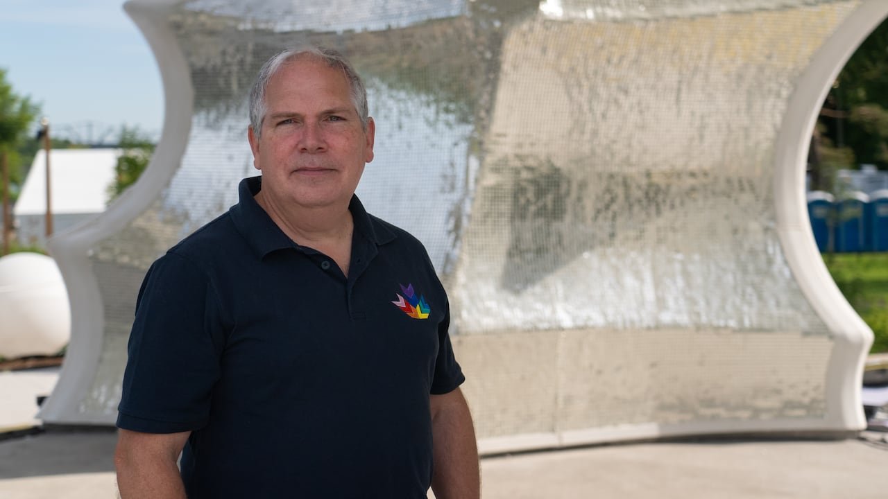 a man stands in front of a reflective wall