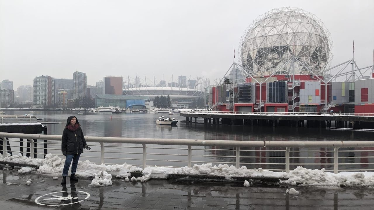 default-39 A woman stands on a snowy sidewalk next to a dome-shaped building.