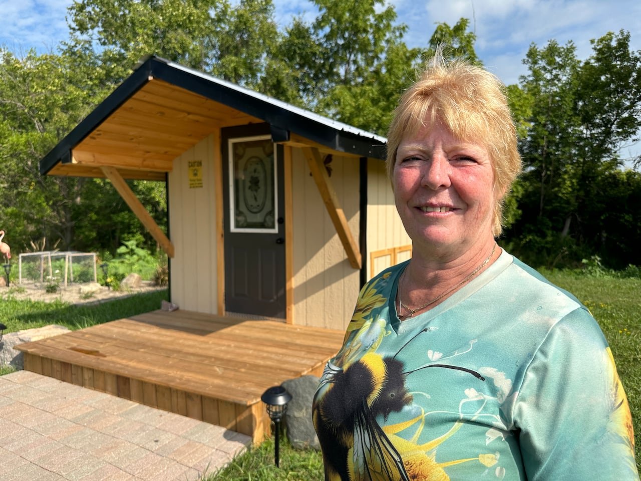 A woman standing in front of a hut.