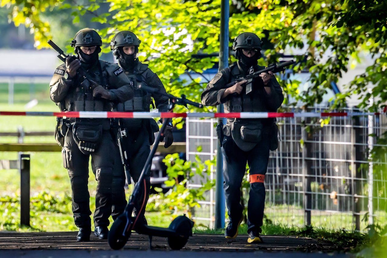 Police officers stand on guard holding guns.